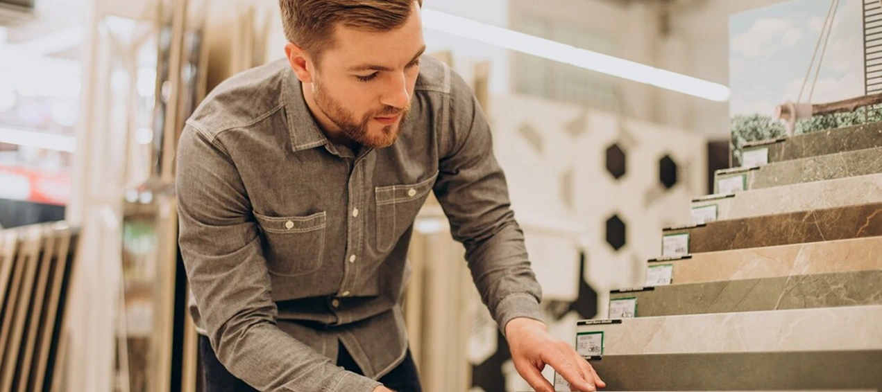 Person in gray shirt examining stone samples in a store, showcasing options for customers.